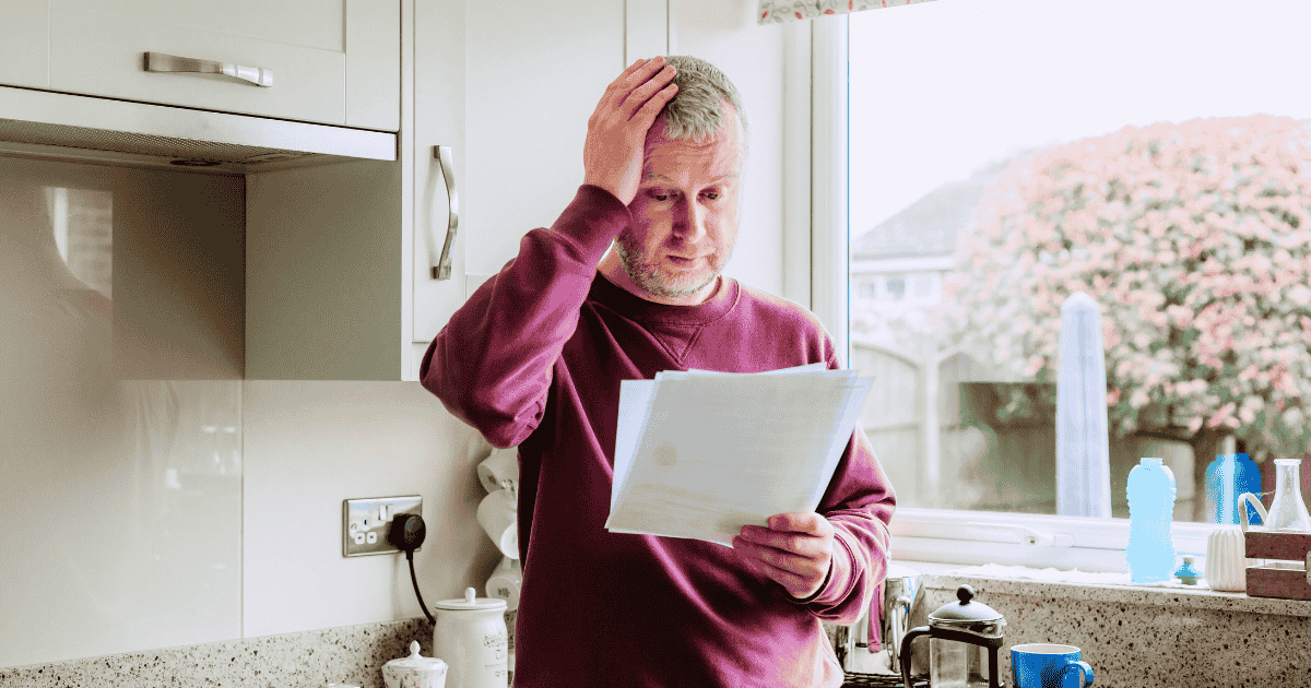 man looking upset while holding heating bill